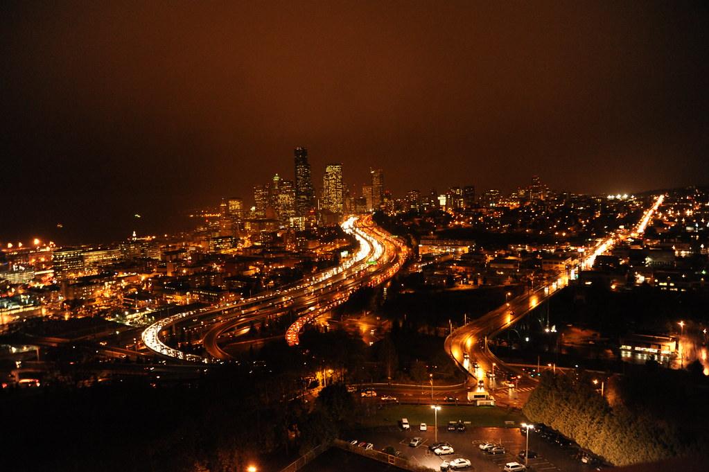 Rain over downtown Seattle at night, with freeway lights below